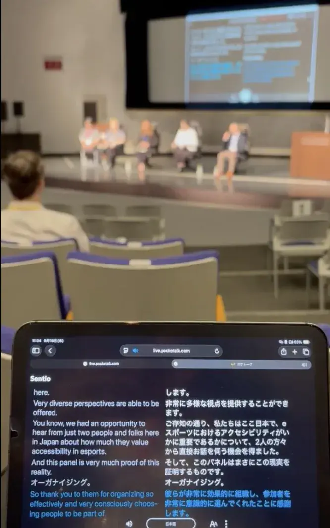 客席の参加者が手元のタブレットでSentioの翻訳画面を見ながら聴講している様子